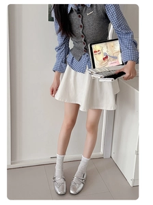Detail of white ruffle socks paired with silver ballet flats and a gray knit vest set