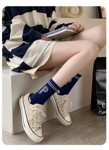 Detail of dark blue crew socks with white stripes and P embroidery paired with sneakers