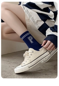 Detail view of navy blue mid-calf socks with white P embroidery and canvas sneakers
