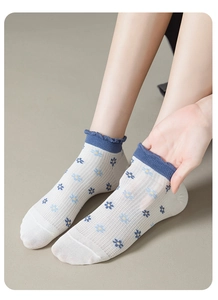 Détail de chaussettes en maille respirante pour femme avec motifs floraux bleus et volants