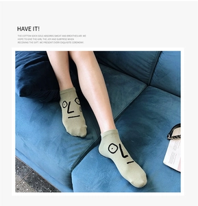Detail of light green cotton socks with minimalist funny faces on a blue velvet sofa