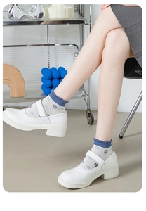 Détail de chaussettes claires à motif floral bleu et bordure à volants avec chaussures blanches