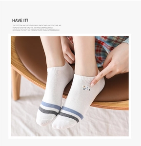 Detail of white cotton boat socks with stripes and animal embroidery on a model foot