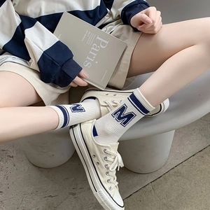 Mid-calf white athletic socks with navy stripes and M letter for a trendy preppy look
