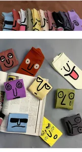 Flat lay of colorful cotton socks with funny cartoon faces on an art magazine background