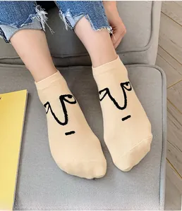 Close-up of beige cotton crew socks with minimalist cartoon face embroidery detail