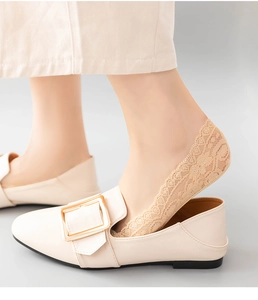 Close-up of beige lace no-show socks with non-slip silicone edge worn with flat shoes