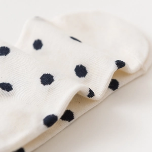 Soft white knit low-cut socks with black polka dot patterns and fine texture
