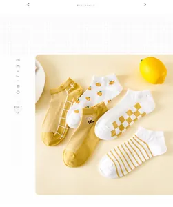 Cinq paires de chaussettes en coton jaune avec motifs fleurs et rayures posées à plat