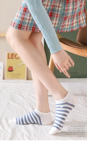 Detail shot of low-cut blue striped socks with cute cartoon embroidery on foot side