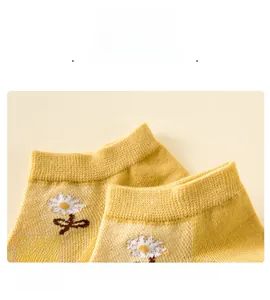 Détail du bord élastique sur chaussettes en coton jaune avec broderie de fleurs blanches