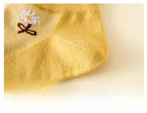 Détail du talon de chaussette en coton jaune avec broderie marguerite et couture soignée
