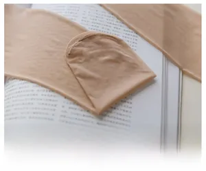Macro view of flat stitched toe seams on sheer nude nylon stockings over an open book