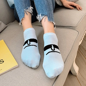 Light blue cotton ankle socks with cartoon eyes on a gray sofa background
