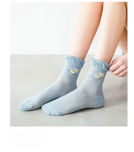 Detail of light blue mesh crew socks with daisy embroidery and wavy ruffle cuff