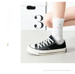 Detail of white cotton mid-calf socks with blue flower patterns and wavy textures