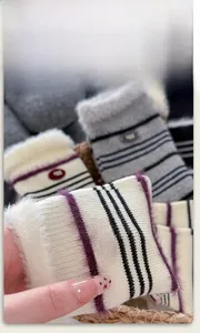 Macro view of knit striped winter socks with white faux fur trim and red egg logo