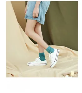 Detail of teal ribbed crew socks paired with white canvas shoes and a denim skirt