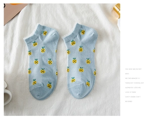 Dettaglio di calzini in cotone azzurro con ricami a forma di simpatici ananas gialli