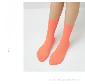 Macro detail of breathable coral orange ribbed cotton crew socks for women on model