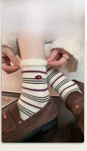 Detail of warm striped mink velvet socks with faux fur trim and gold badge ornament