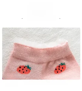 Dettaglio calzino rosa con fragole, bordo elastico e rifinitura in finta pelliccia bianca
