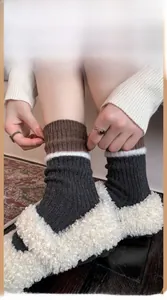 Close-up of tricolor striped wool socks with knit ribbing paired with warm slippers