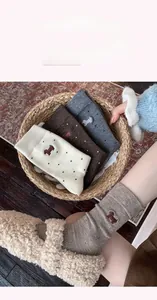 Close-up of cozy cashmere socks with cute dog embroidery in warm autumn tones