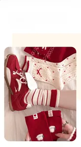 Detail von rot-weißen Neujahrs-Wollsocken mit Welpen-Patch und festlichen Schleifen-Elementen