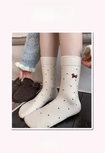 Detail of cashmere socks with cute dog embroidery and black polka dot pattern on beige fabric