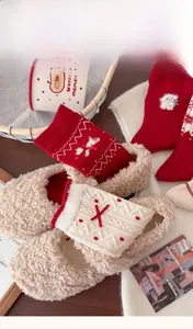 Detail von roten Wollsocken mit Schleifen und Plüschhausschuhen in winterlicher Atmosphäre