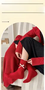 Detail von roten Wollsocken mit zarter weißer Spitzenborte und kleiner Schleifenverzierung