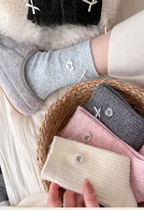 Close-up of wool socks featuring vertical knit texture, sweet bows and heart buttons