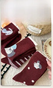 Detail of dark red wool socks with cartoon animal patterns and white fuzzy cuffs