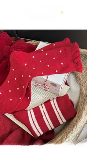 Nahaufnahme dicker roter Wollsocken mit weißen Punkten und Streifen in einem Geschenkkorb