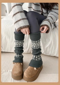 Close-up of thick knitted leg warmers featuring Nordic snowflake patterns in dark grey-green