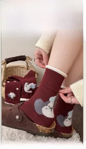 Detailed close-up of dark red wool socks with cute cartoon bear pattern and elastic cuffs