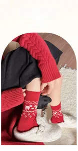 Details von roten Wollsocken mit weißen Rentier-Mustern und süßen Schleifenakzenten
