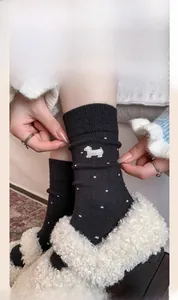 Close-up of black cashmere socks with cute dog embroidery and white polka dots pattern