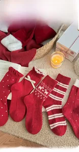Detail von roten Weihnachts-Wollsocken mit Spitzenschleifen und festlichen Mustern