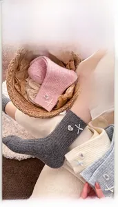 Close-up of wool blend socks featuring silk ribbons and heart-shaped button details