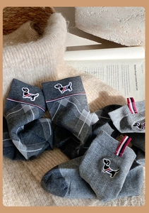 Detail of grey diamond pattern socks with dog embroidery and tricolor stripe tag