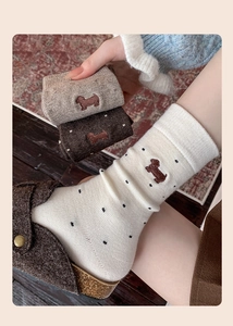 Close-up of dog embroidery and polka dot patterns on soft cashmere knit socks