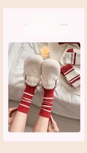 Close-up of thick red striped cashmere socks worn with cozy white plush mule slippers