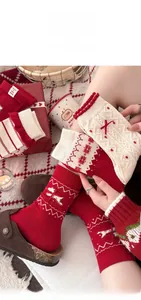 Detail von Weihnachts-Wollsocken mit roten Schleifen, Schneeflocken und Rüschenbündchen