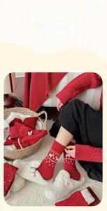 Detail von roten Wollsocken mit Rentier-Mustern und weißen Schleifen-Akzenten für Winter