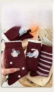 Detail of burgundy wool socks featuring cute animal embroidery and stripe patterns