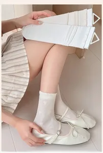 Detail view of white mulberry silk mesh socks with heart patterns and bubble cuffs