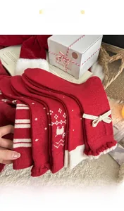 Detail von rot-weißen Weihnachts-Wollsocken mit Rentier-Mustern und Schleifen-Details