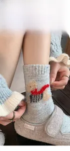 Close-up of blue wool blend sock with colorful speckles and cute dog embroidery